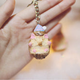 Hand holding a cute hedgehog keychain with pastel-painted details and a tiny party hat.